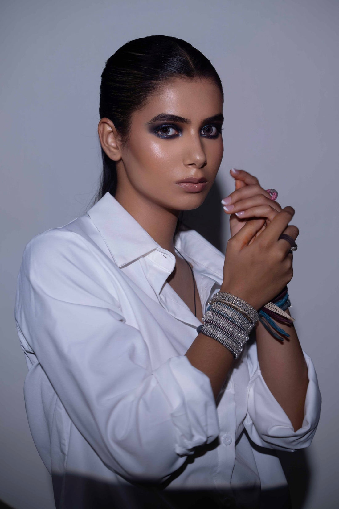 Model in a white shirt wearing Caravan of Stones pavé diamond Stacker bracelets in the new colours, stacked on the wrist