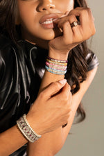 Woman in a black leather jacket wearing colourful Row bracelet stacks