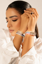 Woman in a white blouse wearing pastel Mini Lisse bracelet stacks on both wrists