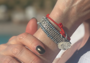 Close-up of a blue thread bracelet with pavé-set natural diamonds, layered with a red cord bracelet