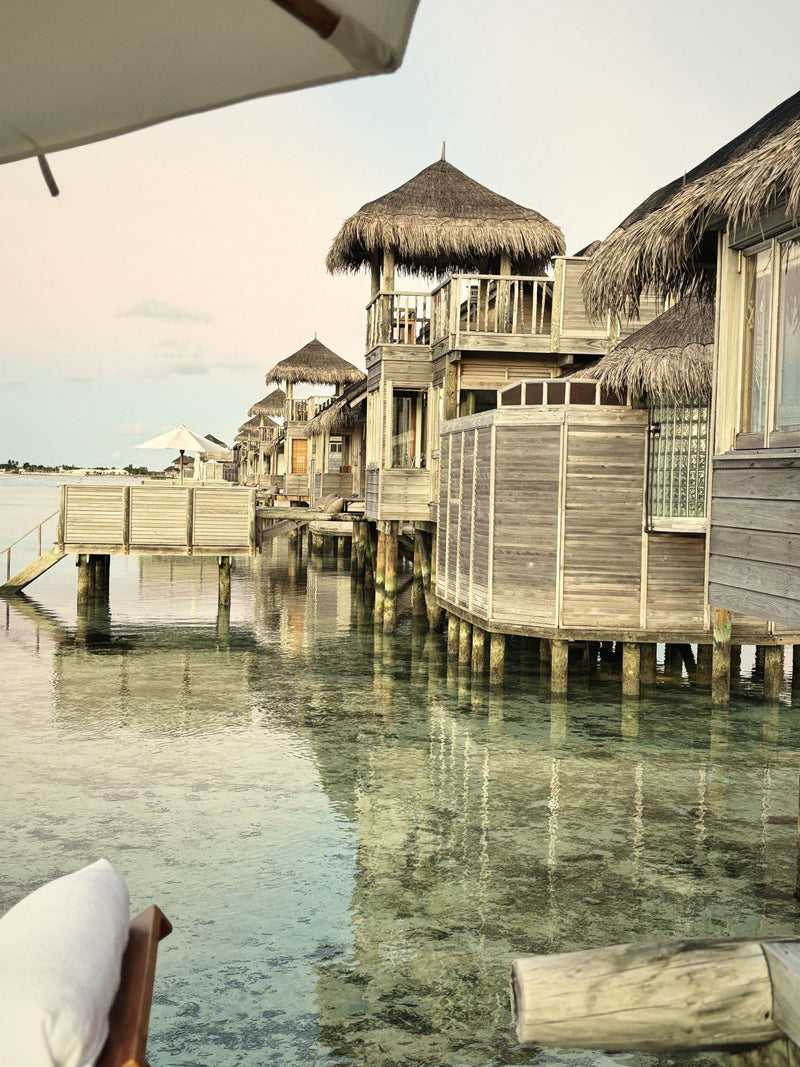 Reclaimed-wood overwater villas with thatched roofs above the lagoon at Gili Lankanfushi, the Maldives