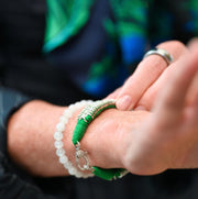 Close-up of a green thread bracelet with pavé-set natural diamonds and a diamond-set clasp being fastened on a wrist