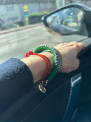 Green thread bracelet with pavé-set natural diamonds worn on a wrist inside a car
