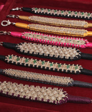 Natural diamond and gemstone thread bracelets in black, gold, pink and claret arranged on burgundy velvet