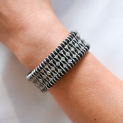 Close-up of a wrist wearing a textured bracelet on a light background