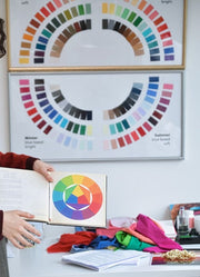 Person holding a color book with a color wheel next to a display of color swatches.