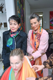 Three women wearing colorful scarves in a room with art on the walls.