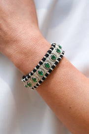 Black thread emerald and diamond bracelet worn on wrist