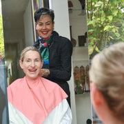 Two women sitting together with a third person looking over their shoulder, in a room with decorative elements.