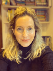 Portrait of a woman wearing a black roll-neck top in front of bookshelves