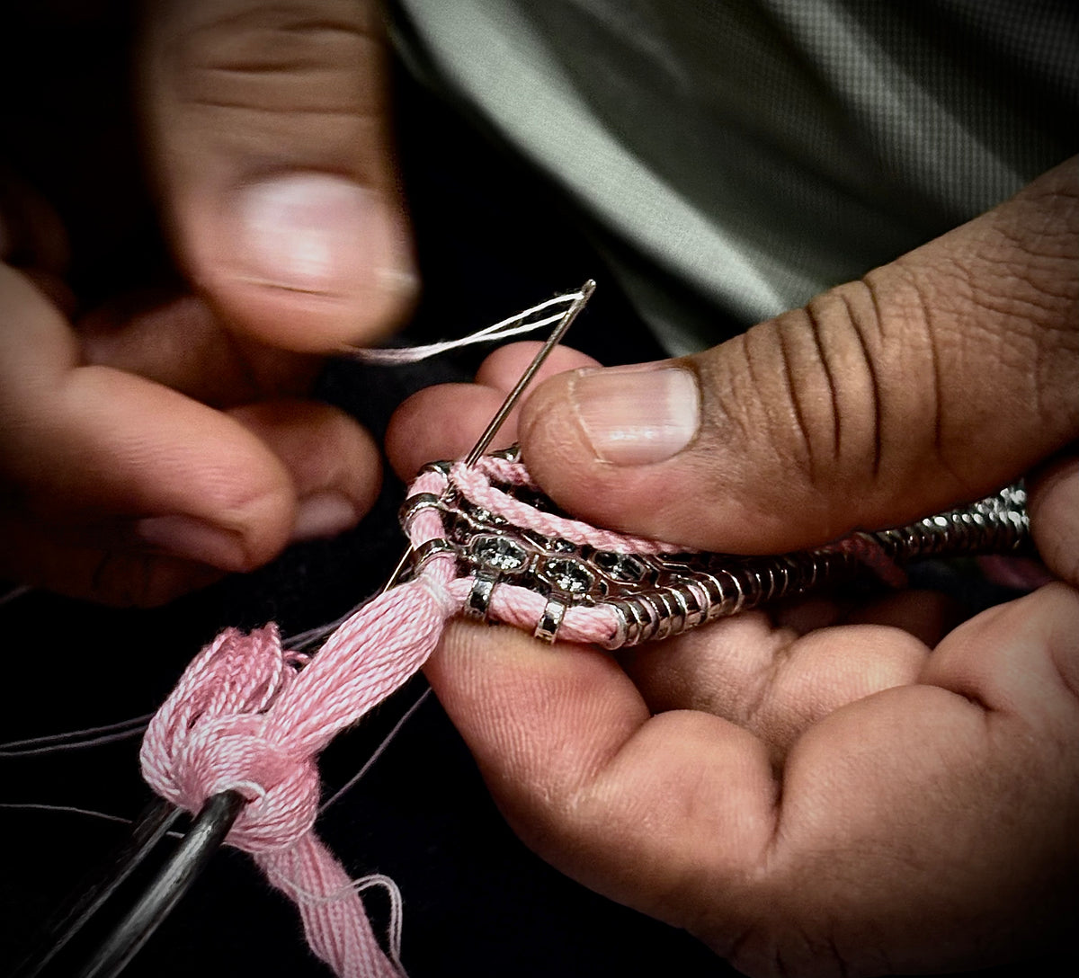 Artisan sewing pink thread into a diamond bracelet by hand