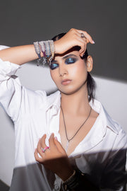 The LOVE Necklace and diamond thread bracelets on a model in a white shirt, in shadow and light