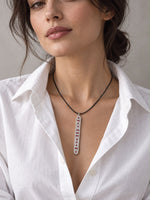 Model in a white shirt wearing the Caravan of Stones LOVE Necklace: an elongated sterling silver pendant pavé-set with diamonds, with rubies spelling LOVE in Morse code, on a black leather cord