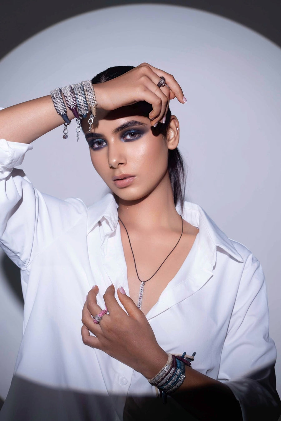 Model in a white shirt wearing Caravan of Stones diamond rings on Linhasita and leather, stacked natural diamond thread bracelets and The LOVE Necklace