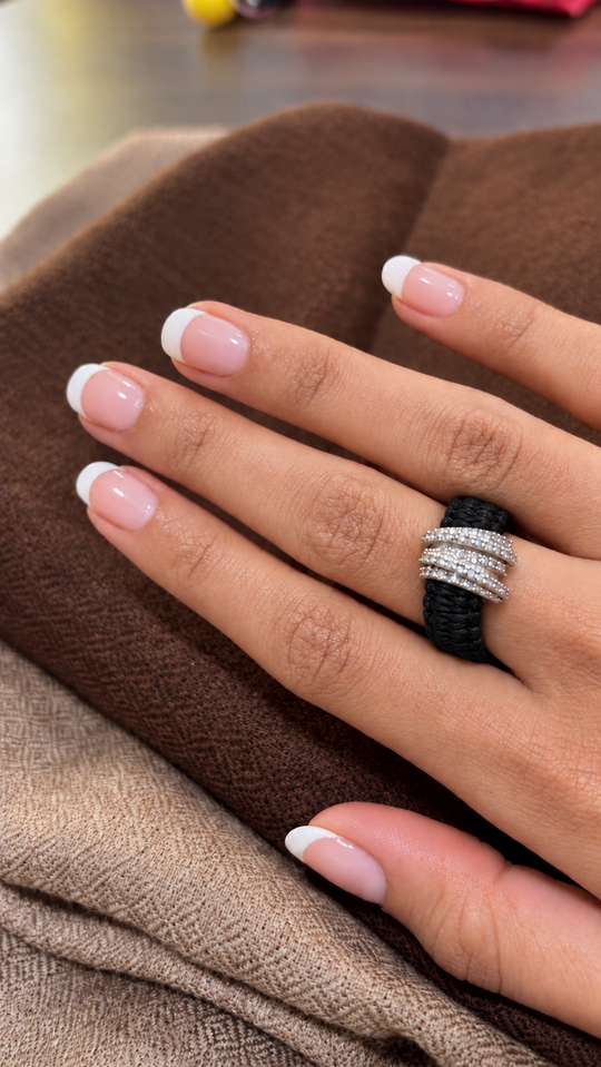 The Diamond Ring in Black Linhasita by Caravan of Stones, with a continuous knotted thread band and pavé diamond silver detail, worn on a hand.