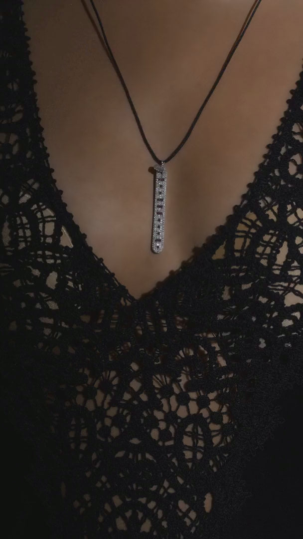 The LOVE Necklace by Caravan of Stones worn over black lace: pavé diamond sterling silver pendant with rubies spelling LOVE in Morse code, on a black cord