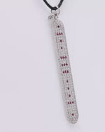 The LOVE Necklace by Caravan of Stones turning in the light: pavé diamond sterling silver pendant with rubies spelling LOVE in Morse code, on a black cord